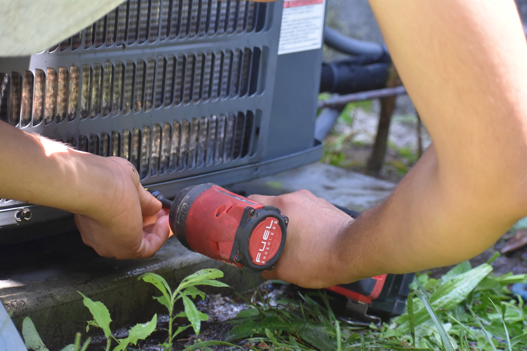 Technician using an impact driver to service an AC unit