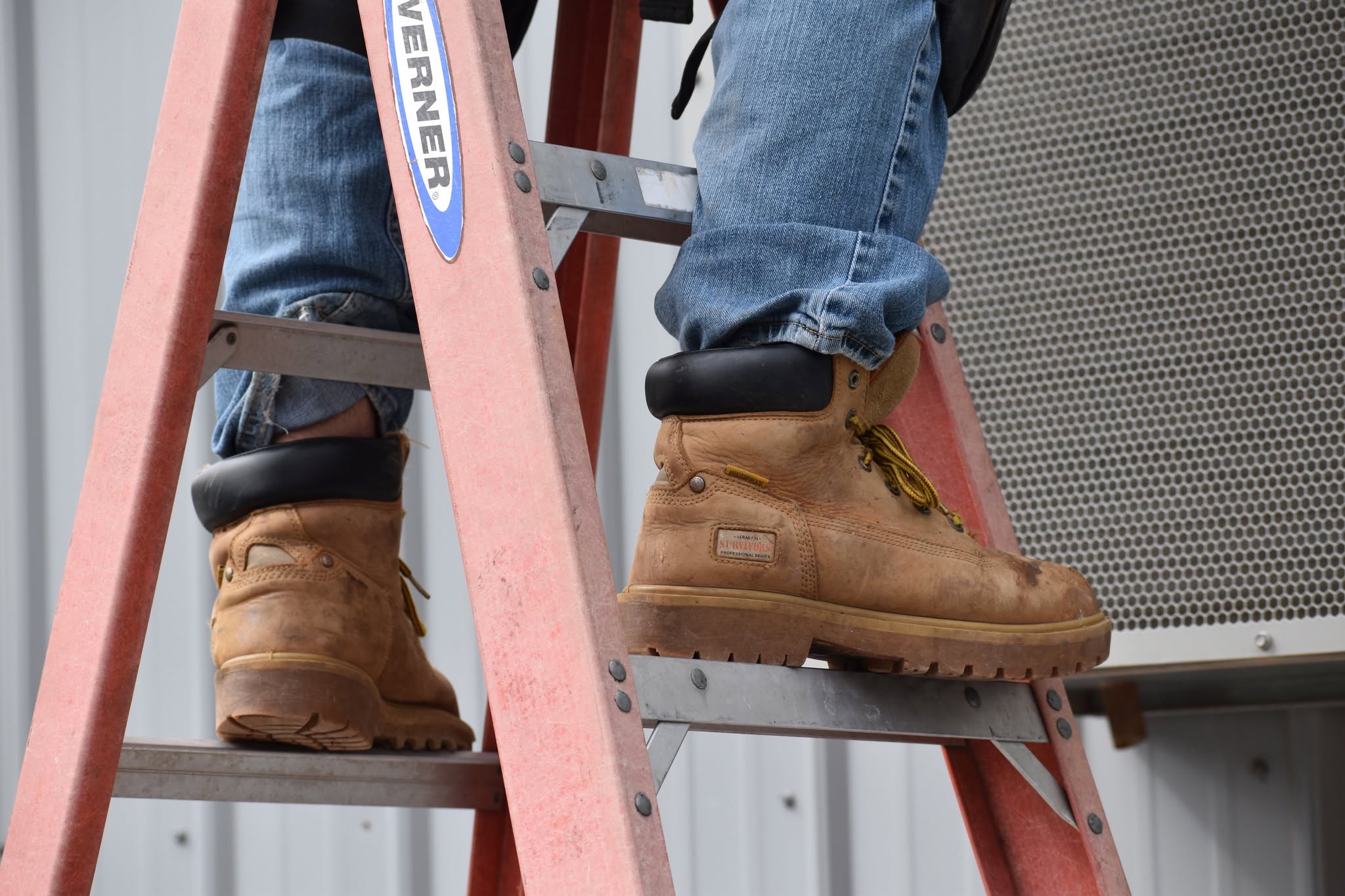Technician climbing a ladder to access a commercial rooftop HVAC unit