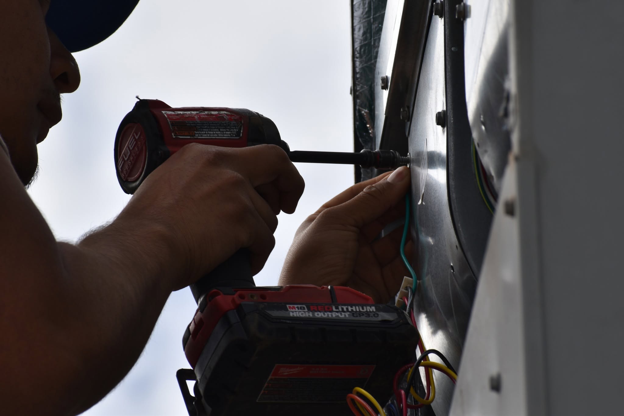 Technician securing an access panel on a rooftop HVAC unit