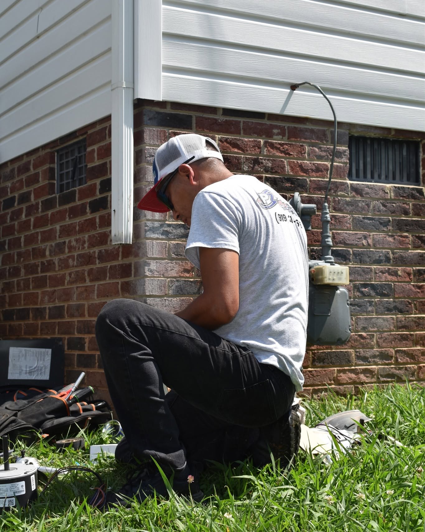 Technician repairing an outdoor electrical motor at a residential home