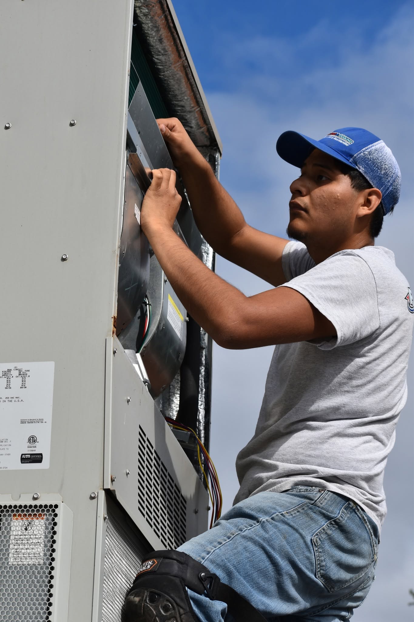 Technician wiring the electrical panel on a rooftop HVAC unit